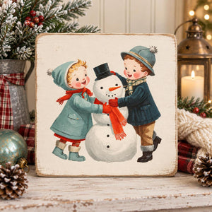 Retro Christmas children building a snowman transfer on a square wooden sign.